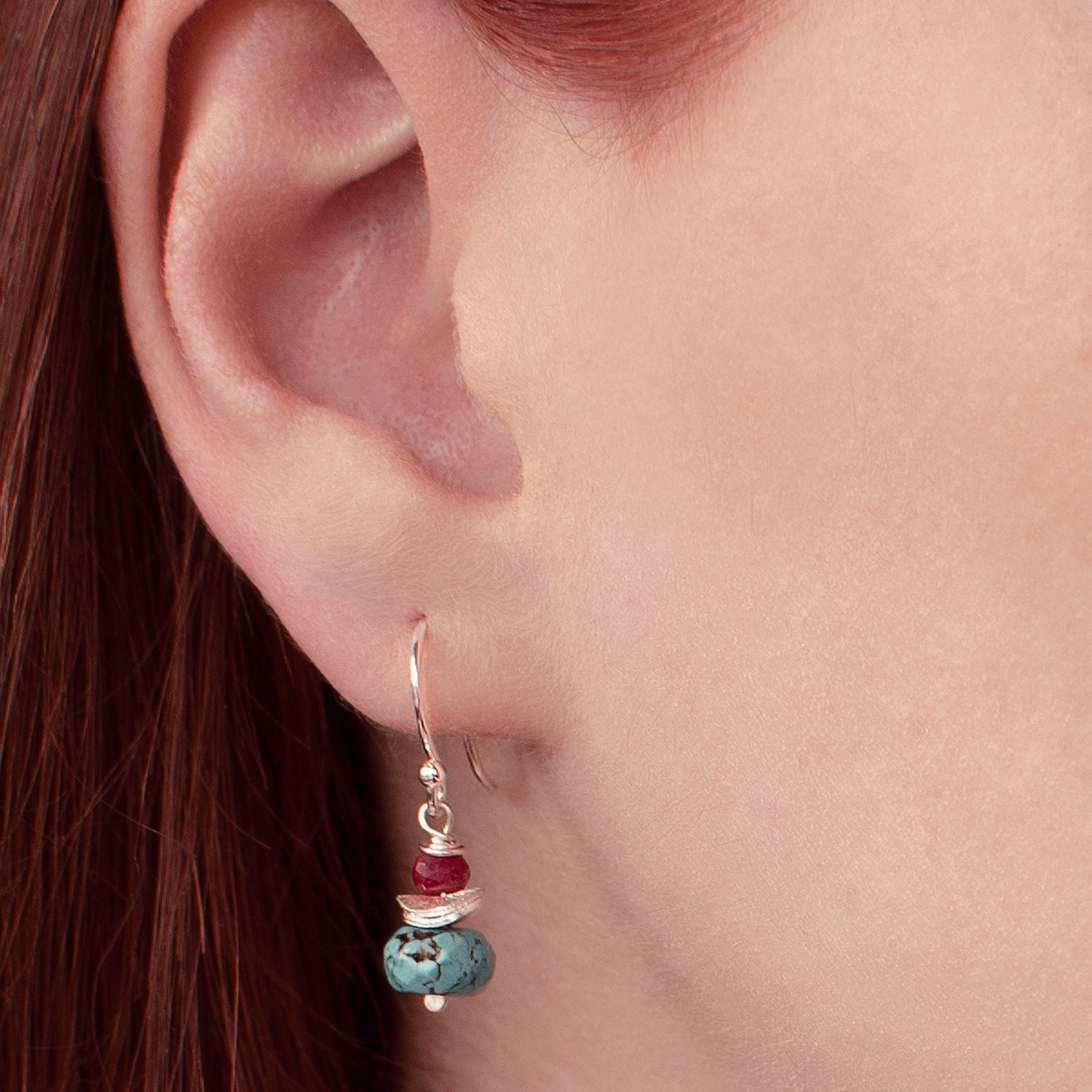 Close up of dangle earring with ruby and turquoise stones