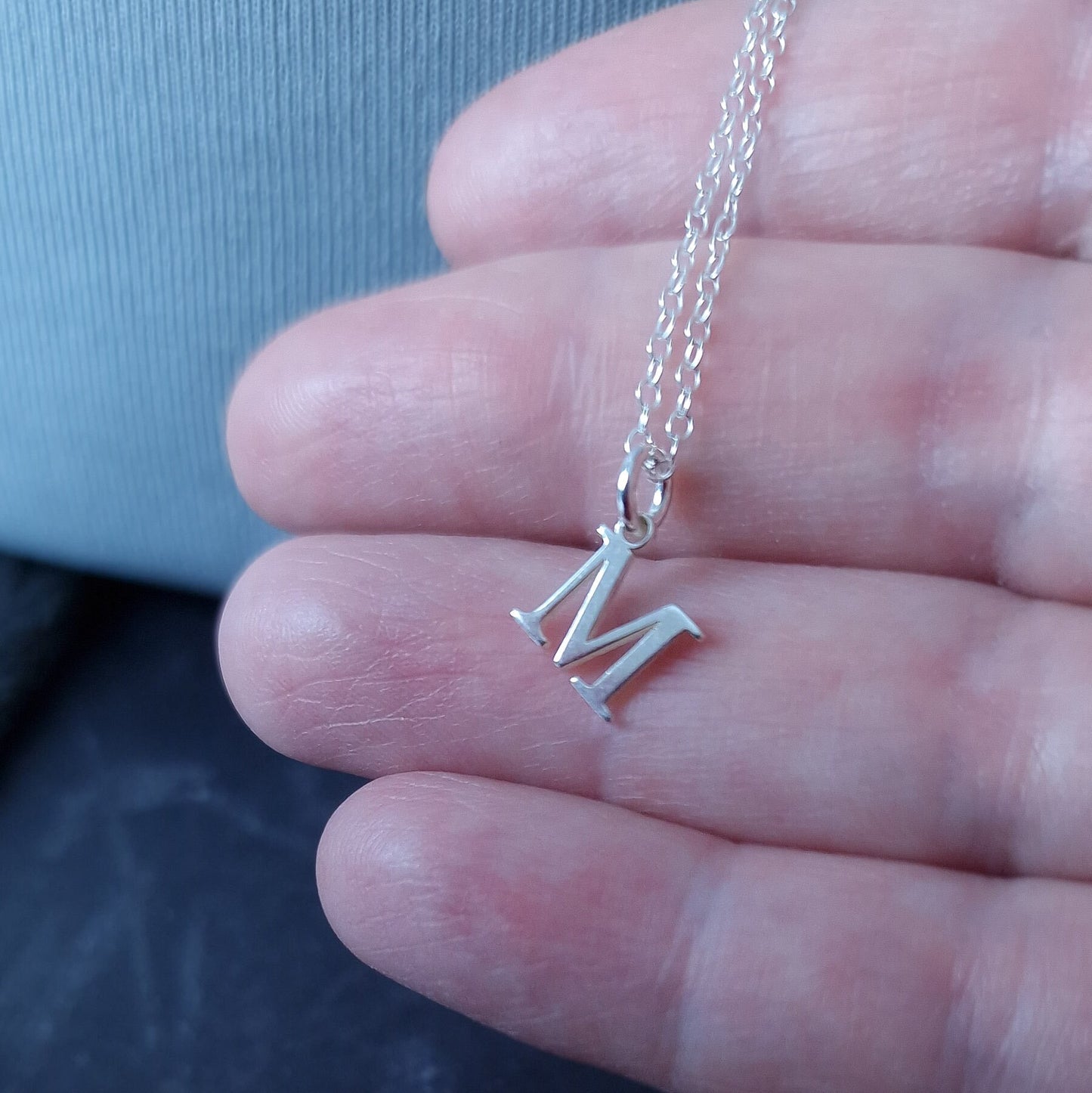 Close up of Sterling Silver Initial Alphabet Necklace in a person's hand