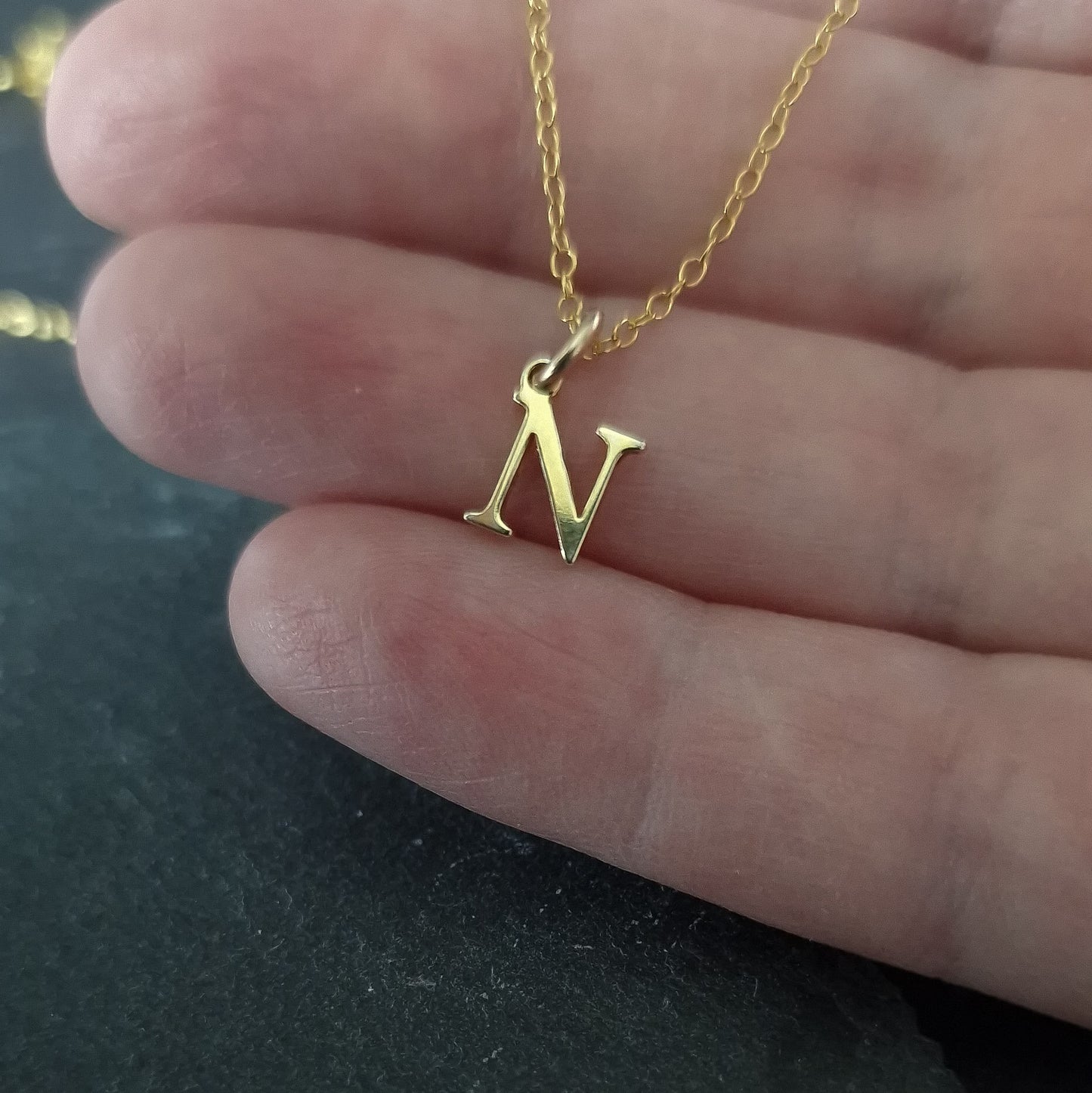 Close up of Gold vermeil silver initial pendant necklace being held in a hand