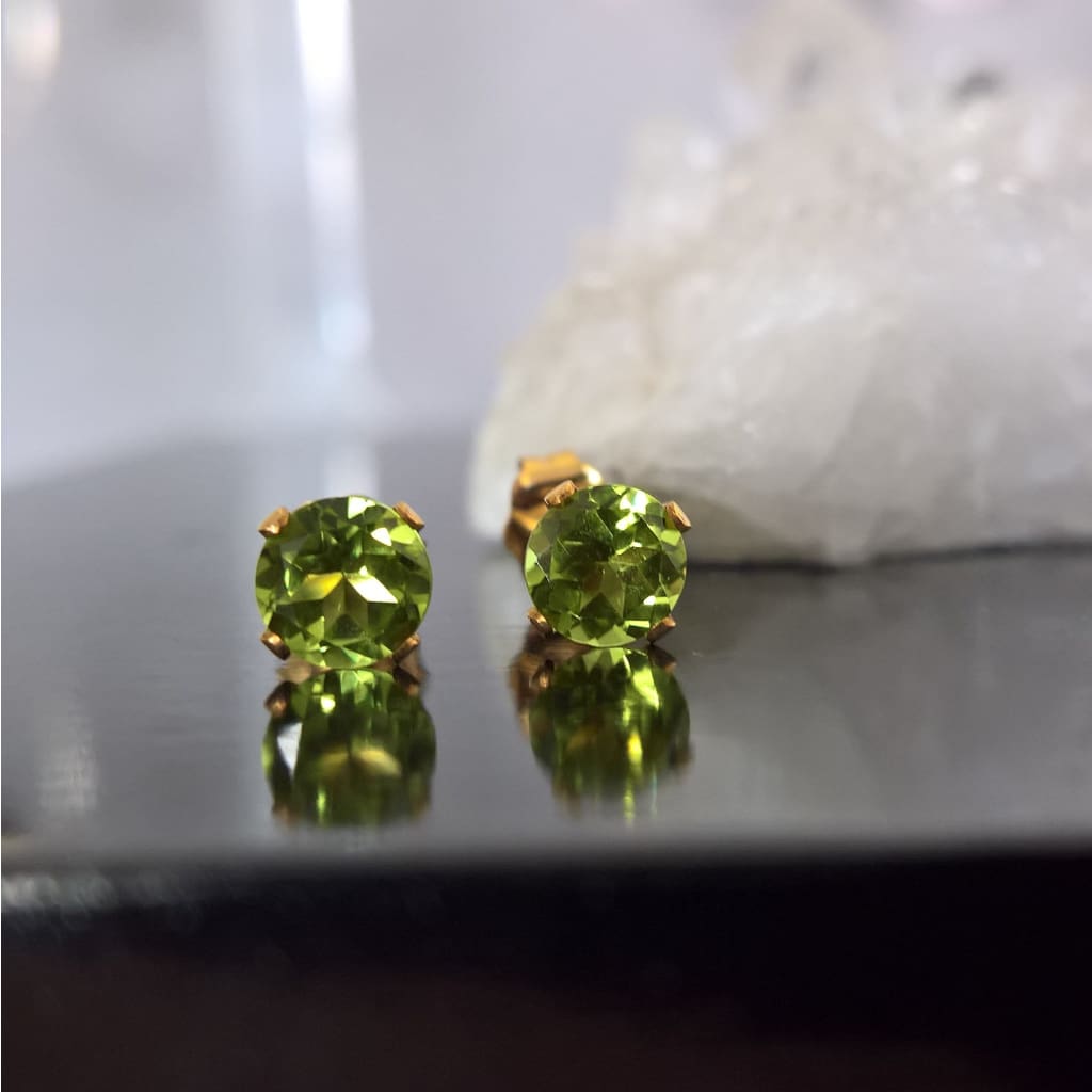 Close up of gold filled peridot stud earrings sitting on a quartz crystal - Marie Nicole Bijoux