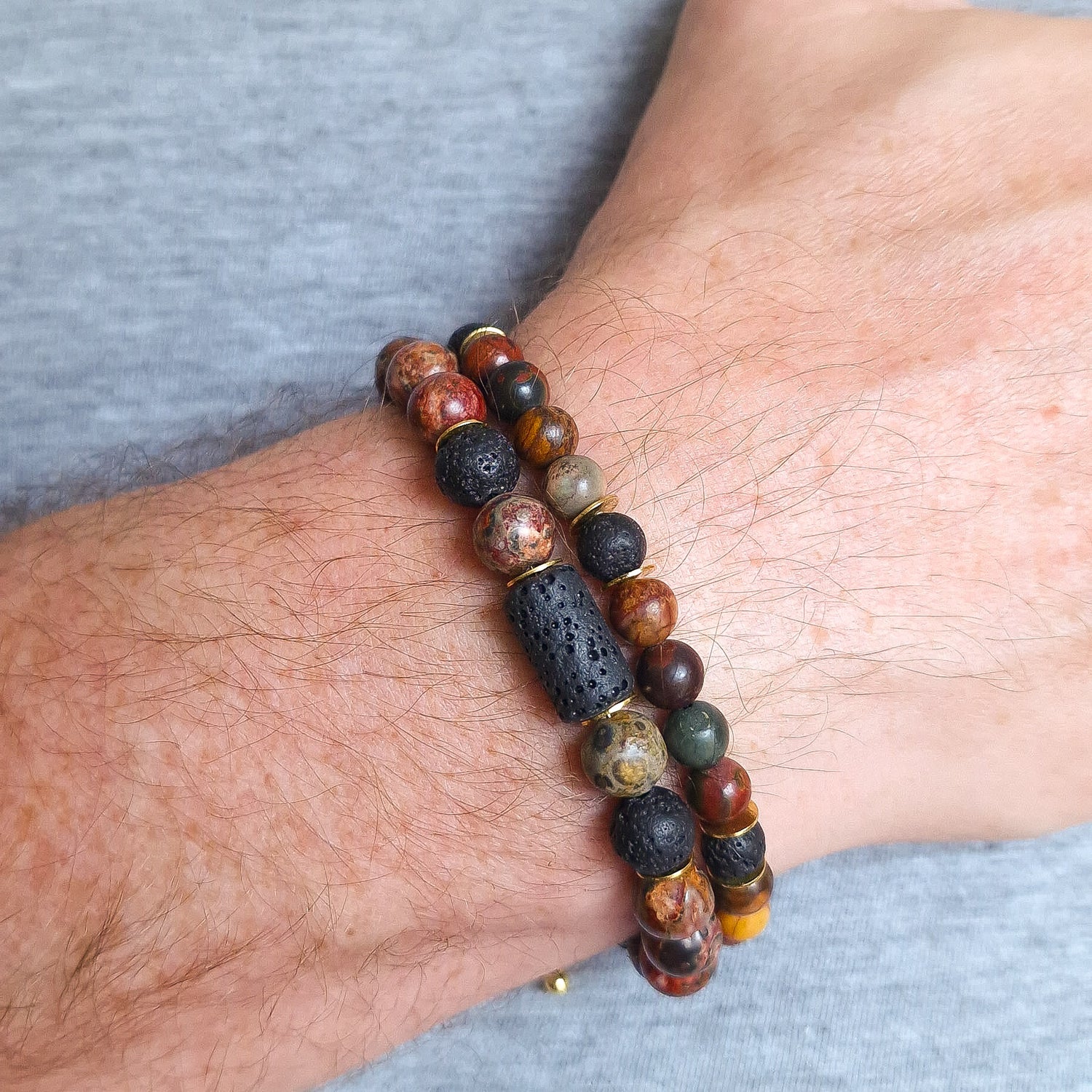 Close up of two jasper natural stone bracelet's on a man's wrist.