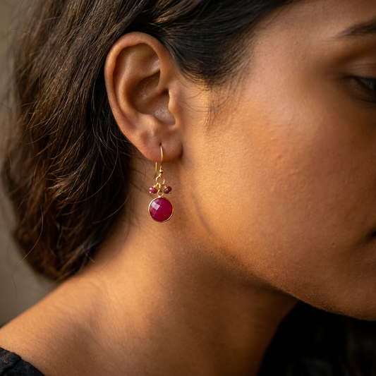 Side view of a woman wearing ruby gold vermeil silver circle drop earrings