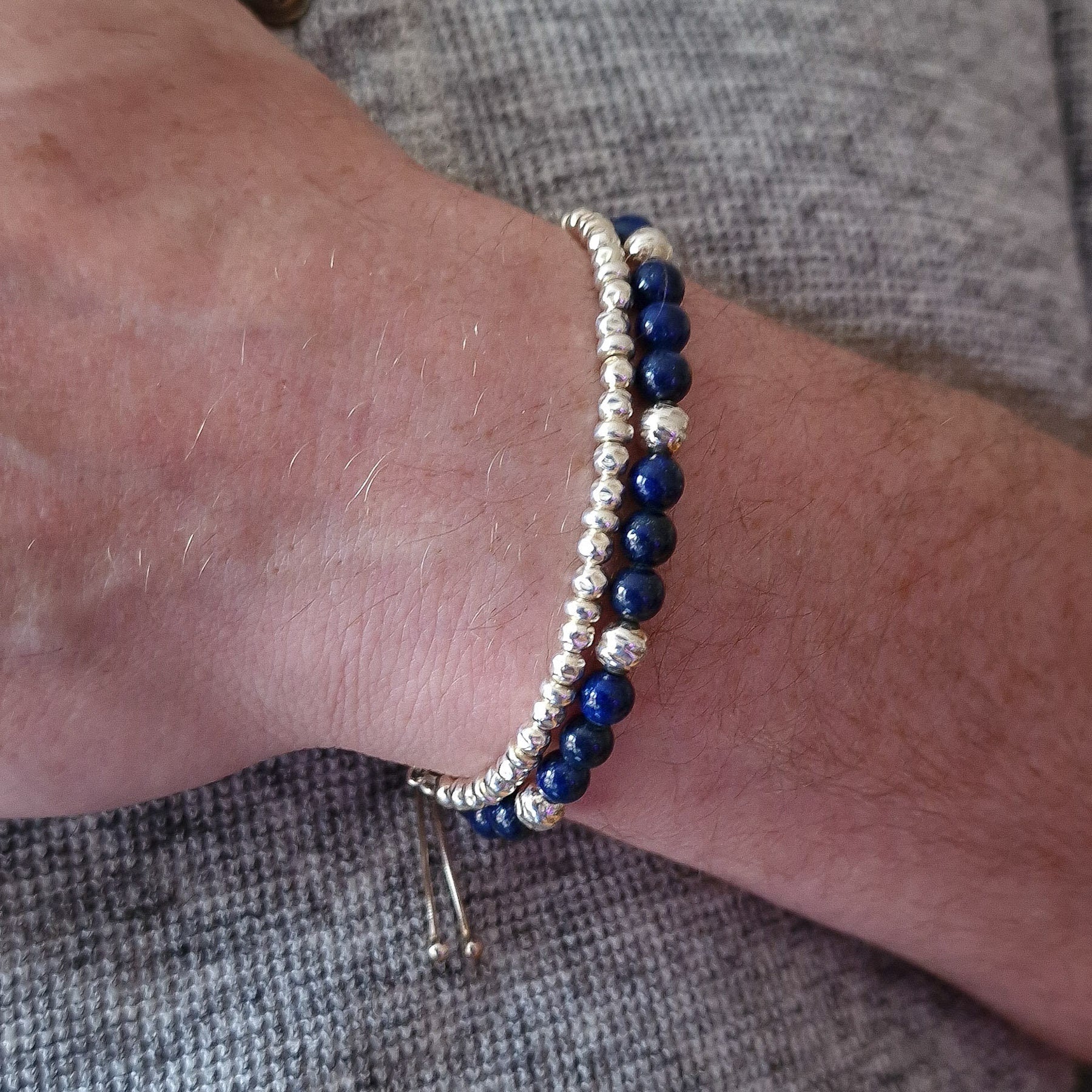 Marie Nicole Bijoux - Close up of mens wrist with two silver and gemstone bracelets